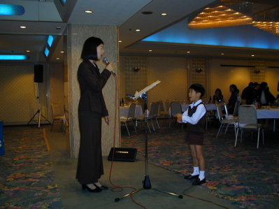 Band chief's wife sings a song Kawa no nagare no yooni (Like a river's stream), and her son is conducting the band.